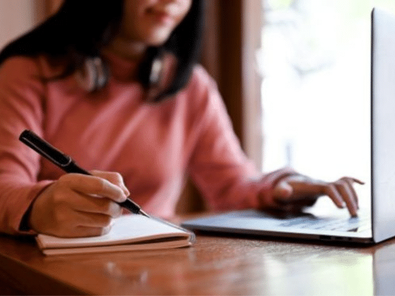 Person using laptop and taking notes